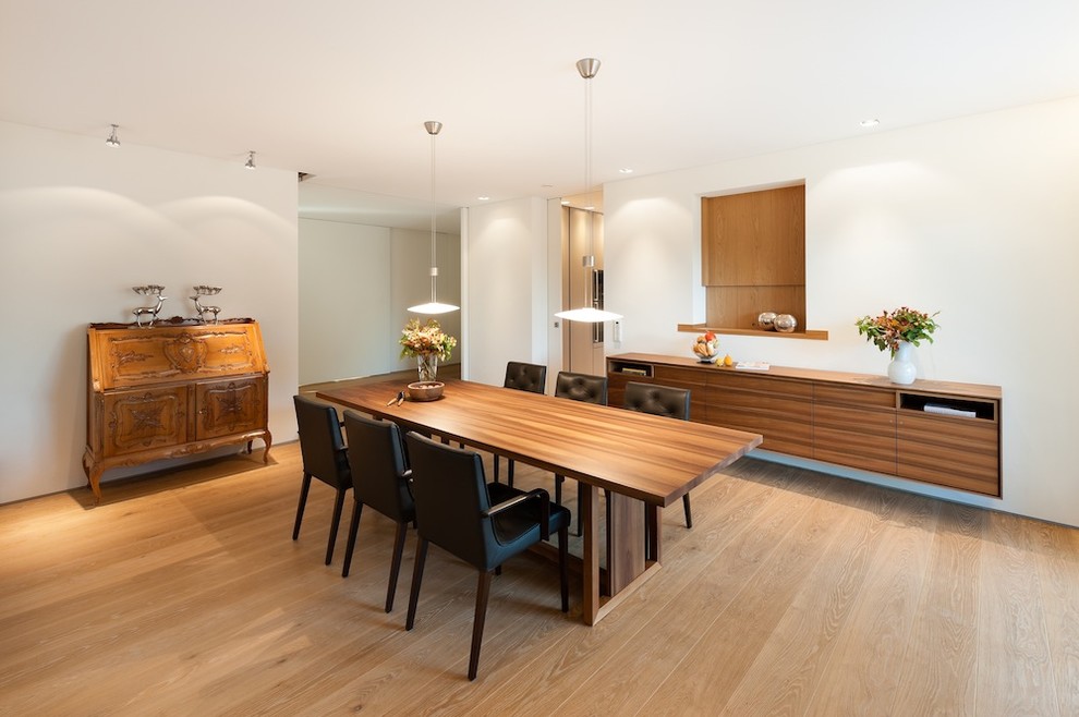 Diseño de comedor moderno de tamaño medio cerrado con paredes blancas y suelo de madera en tonos medios