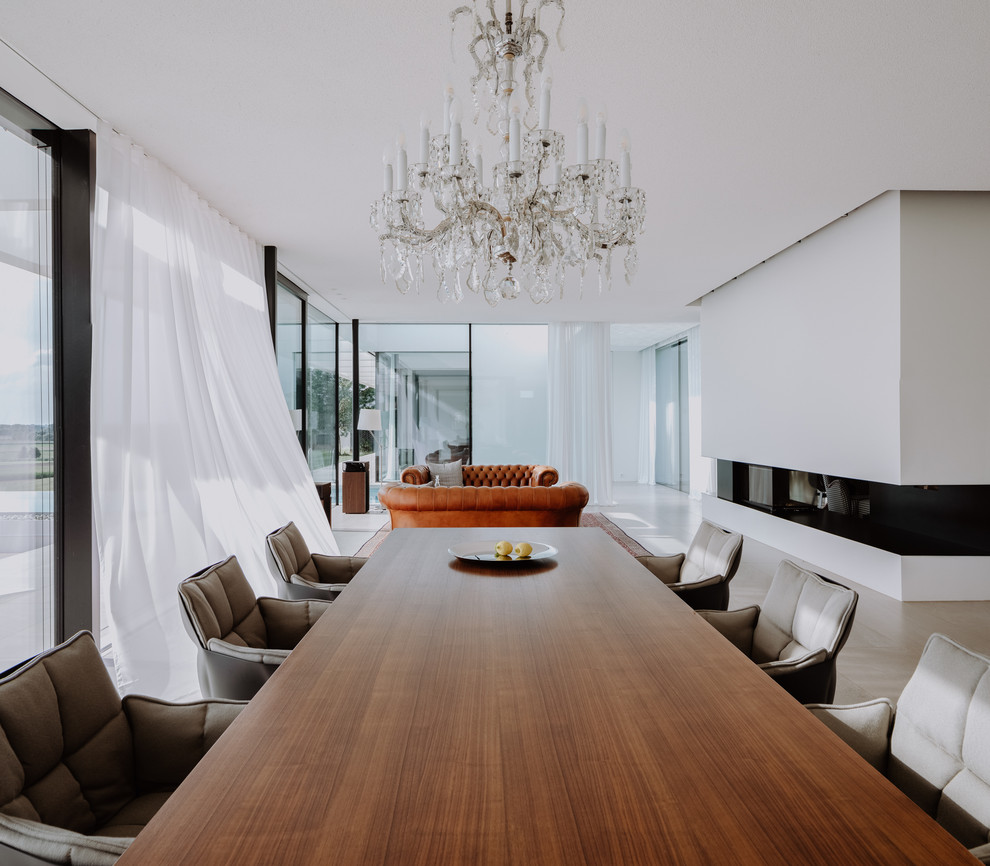 Пример оригинального дизайна: большая гостиная-столовая в стиле модернизм с белыми стенами, полом из известняка, печью-буржуйкой, фасадом камина из штукатурки и серым полом