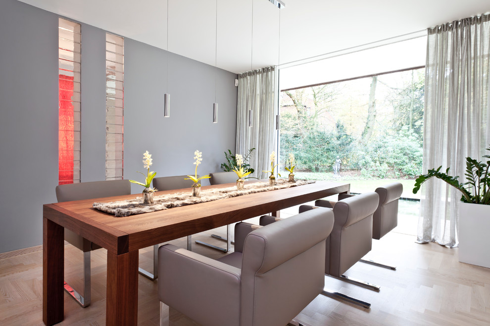 На фото: столовая в современном стиле с серыми стенами и светлым паркетным полом без камина с