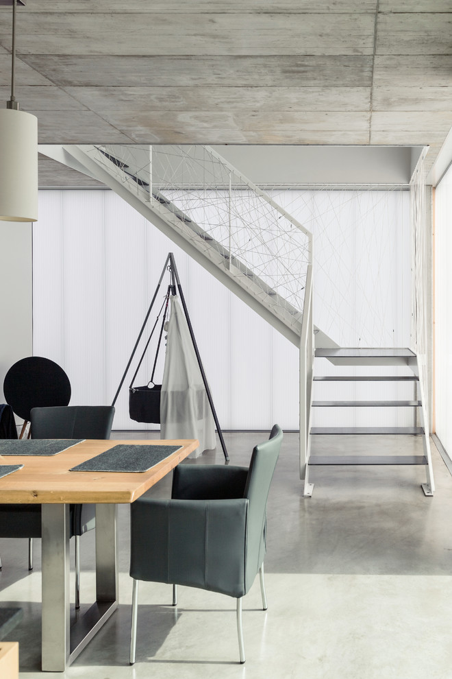 Esempio di una sala da pranzo aperta verso il soggiorno moderna di medie dimensioni con pavimento in cemento e pavimento grigio