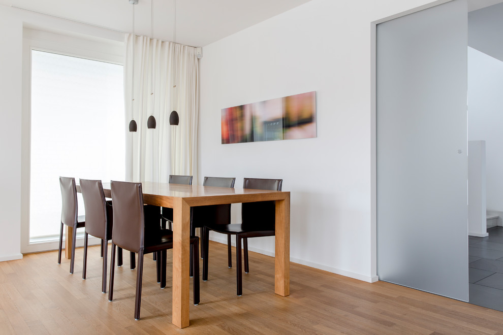 Mittelgroßes Modernes Esszimmer mit weißer Wandfarbe, braunem Holzboden und braunem Boden in Düsseldorf