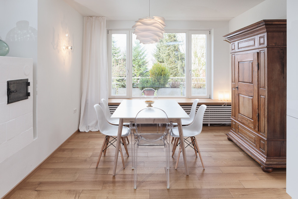 Immagine di una sala da pranzo aperta verso il soggiorno scandinava di medie dimensioni con pareti bianche, pavimento in legno massello medio e stufa a legna