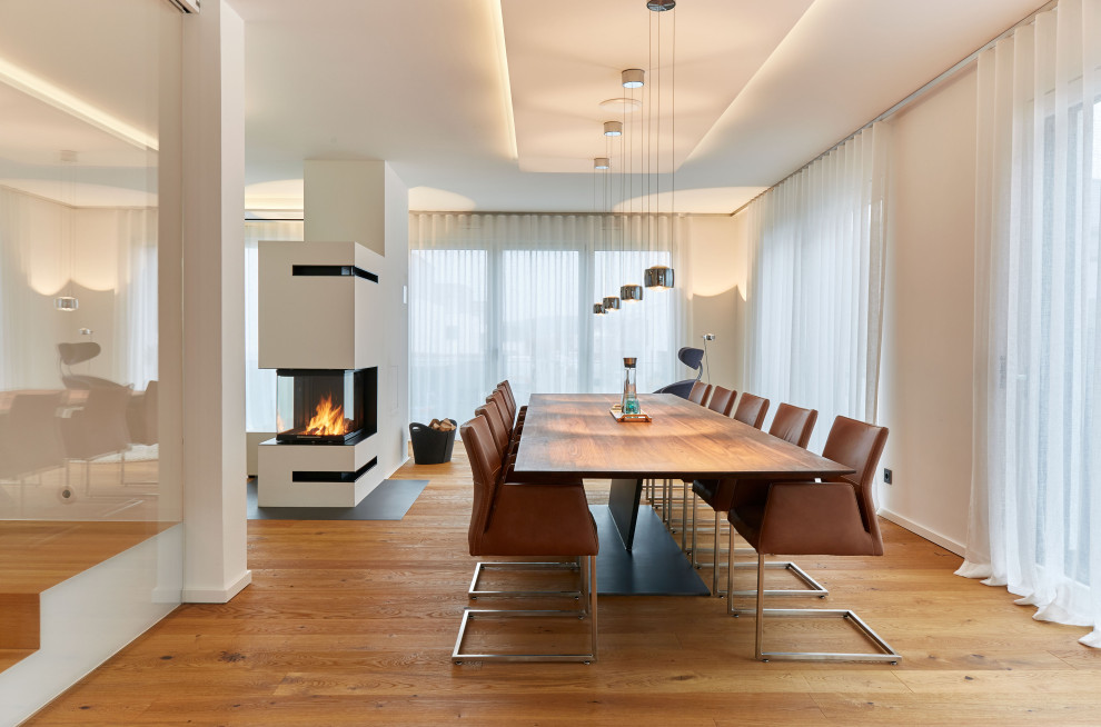 Moderne Wohnküche mit weißer Wandfarbe, gebeiztem Holzboden, Kaminofen und verputzter Kaminumrandung in Frankfurt am Main