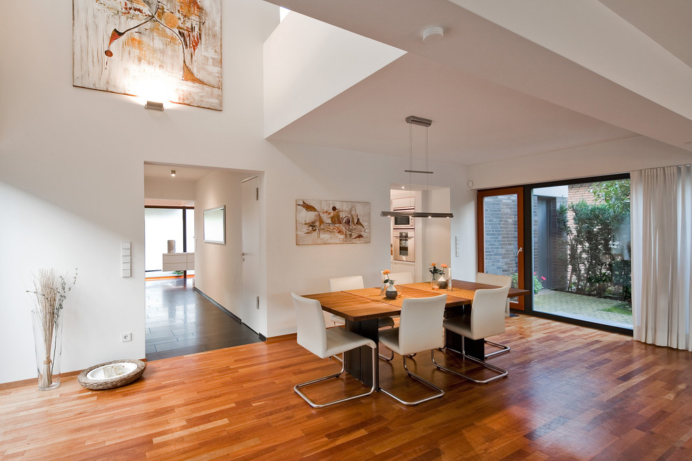 Foto di una grande sala da pranzo aperta verso il soggiorno minimal con pareti bianche e pavimento in legno massello medio