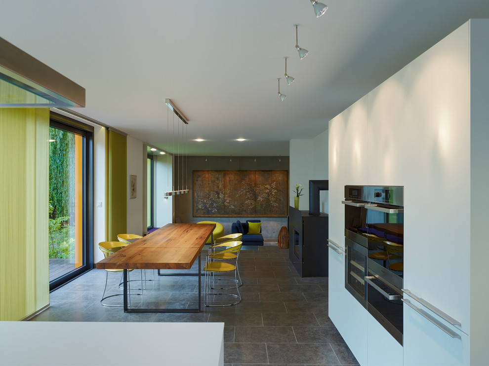 Immagine di una sala da pranzo aperta verso il soggiorno minimal di medie dimensioni con pareti bianche, stufa a legna e cornice del camino in metallo