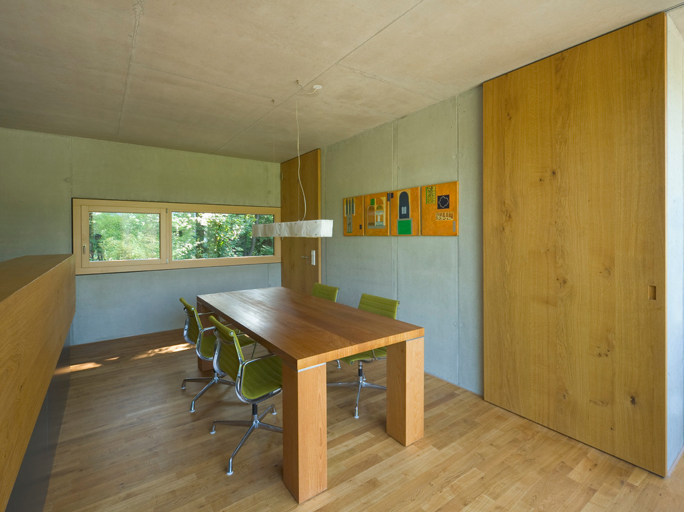 Imagen de comedor urbano de tamaño medio cerrado con suelo de madera clara y paredes blancas