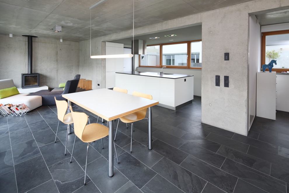 Immagine di una grande sala da pranzo aperta verso il soggiorno design con pareti grigie e pavimento in ardesia
