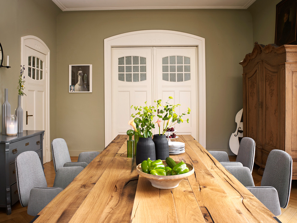 Cette photo montre une salle à manger tendance fermée avec un mur vert et un sol en bois brun.