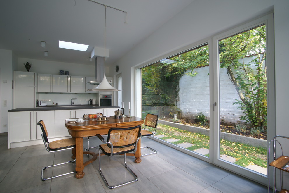 Стильный дизайн: кухня-столовая среднего размера в современном стиле с белыми стенами и серым полом - последний тренд