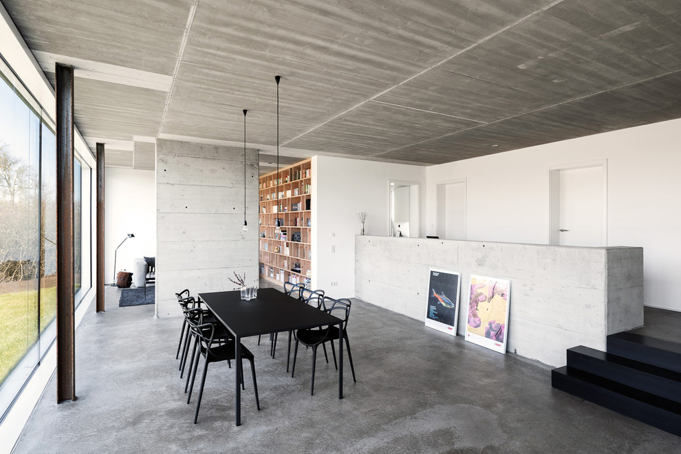 На фото: гостиная-столовая в стиле модернизм с белыми стенами, бетонным полом и серым полом без камина