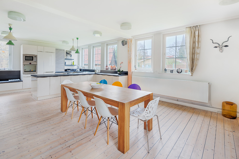 Réalisation d'une très grande salle à manger ouverte sur la cuisine champêtre avec un mur blanc, parquet clair et aucune cheminée.