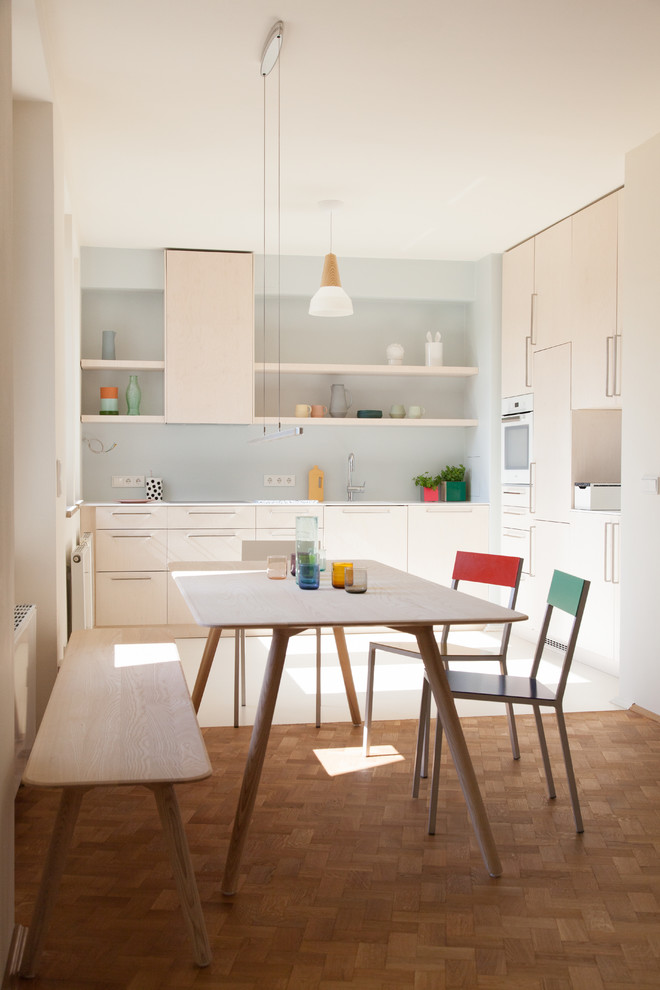 На фото: маленькая кухня-столовая в скандинавском стиле с белыми стенами, паркетным полом среднего тона и коричневым полом для на участке и в саду с