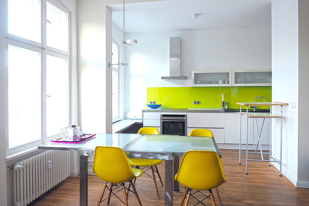 Mittelgroße Moderne Wohnküche ohne Kamin mit weißer Wandfarbe und braunem Holzboden in Berlin