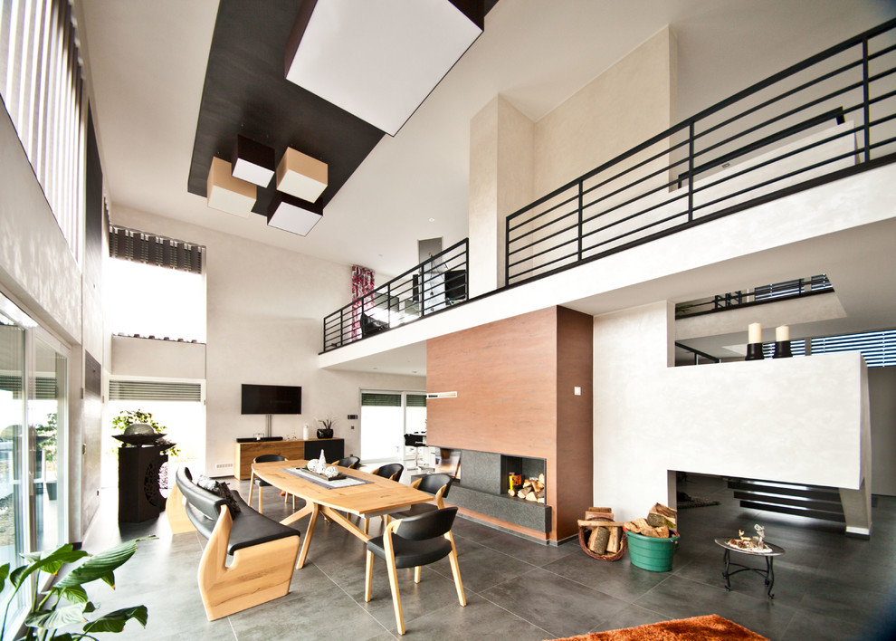 Diseño de comedor contemporáneo extra grande abierto con paredes beige, suelo de pizarra, estufa de leña y suelo negro