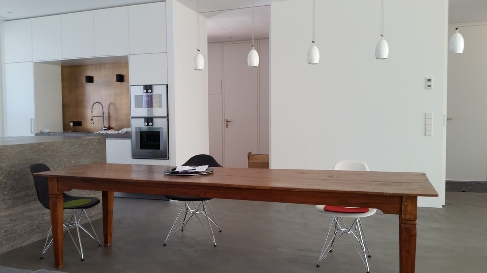 Immagine di una sala da pranzo design con pareti bianche e pavimento in cemento