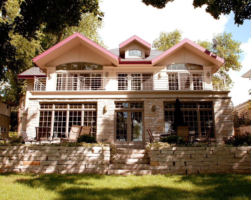 Cette image montre une grande façade de maison beige traditionnelle en pierre à un étage avec un toit à deux pans.