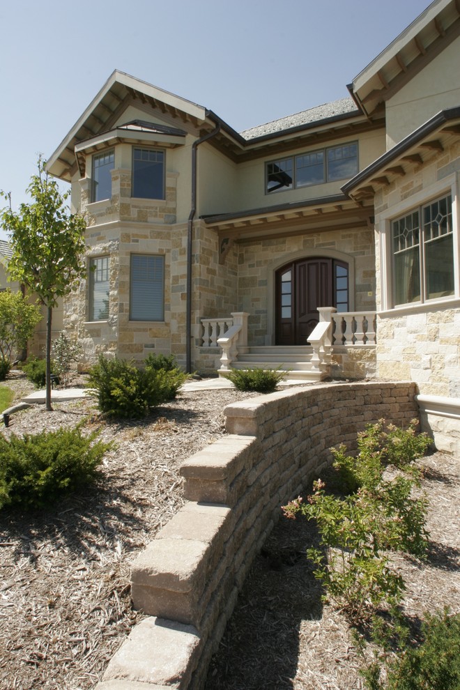 Photo of a large and beige classic two floor house exterior in Other with stone cladding and a pitched roof.