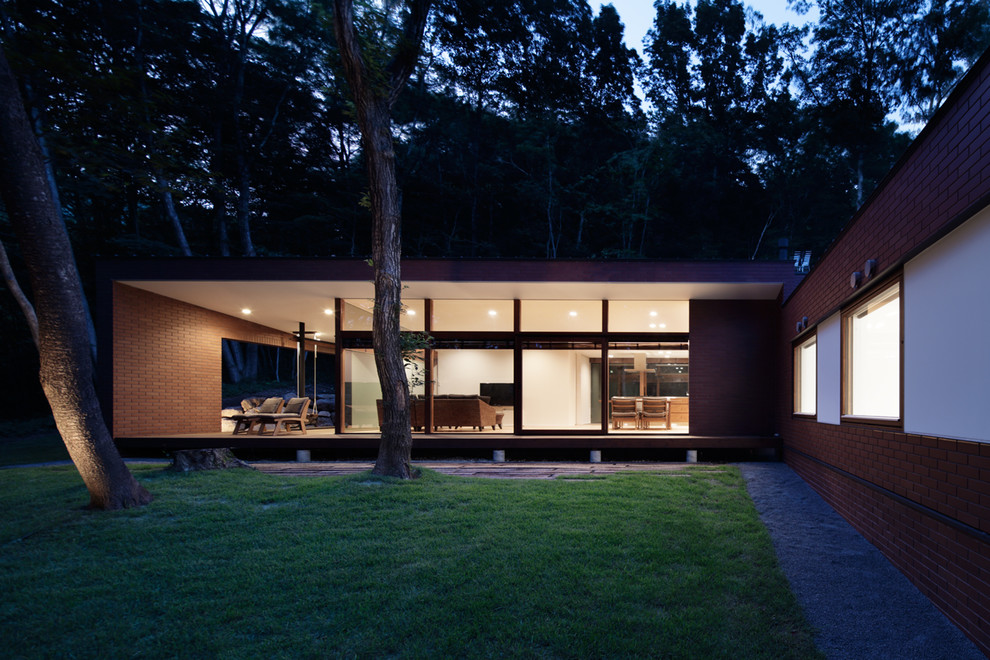 Imagen de fachada de casa marrón minimalista a niveles con revestimiento de ladrillo, tejado a dos aguas y tejado de metal
