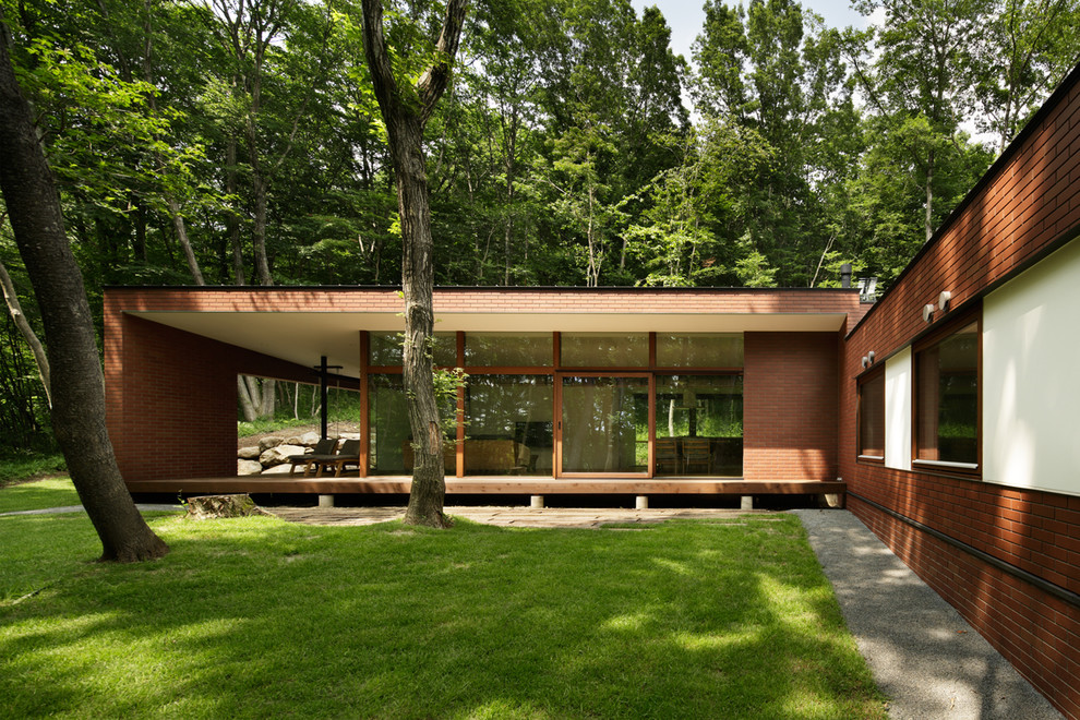 Foto på ett funkis brunt hus i flera nivåer, med tegel, pulpettak och tak i metall