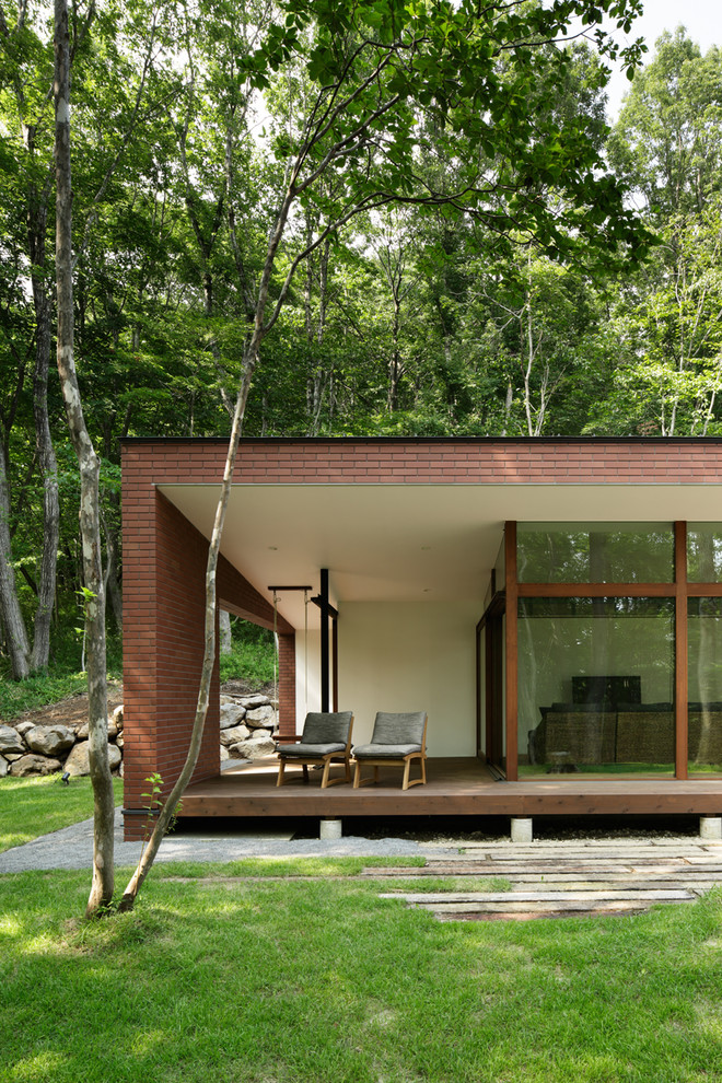 Diseño de fachada de casa marrón minimalista de tamaño medio a niveles con revestimiento de ladrillo, tejado a dos aguas y tejado de metal