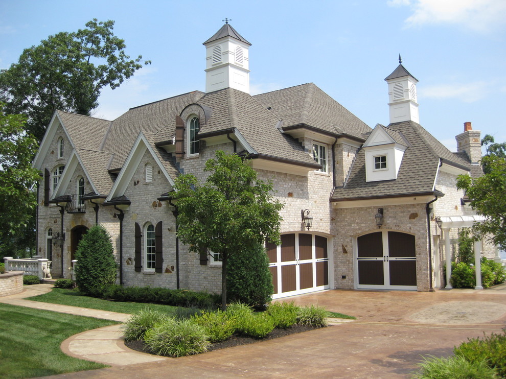 Пример оригинального дизайна: огромный, двухэтажный, бежевый частный загородный дом в стиле кантри с комбинированной облицовкой, двускатной крышей и черепичной крышей