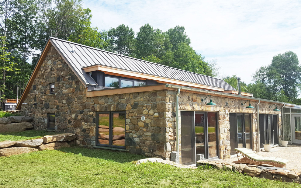 Aménagement d'une façade de maison beige campagne en pierre de taille moyenne et de plain-pied avec un toit à deux pans et un toit en métal.
