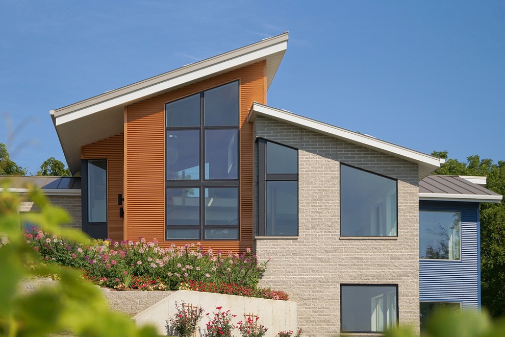 Ejemplo de fachada beige actual de tamaño medio de una planta con revestimientos combinados y tejado de un solo tendido