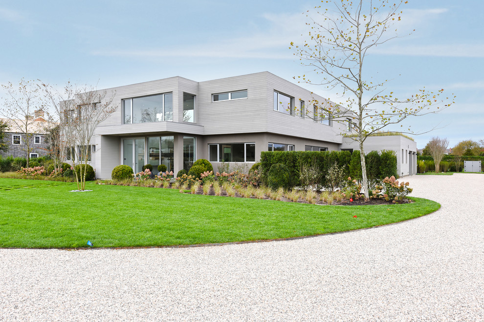 Aménagement d'une très grande façade de maison grise contemporaine à un étage avec un toit plat.