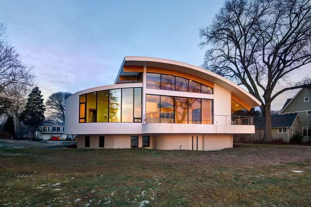 Пример оригинального дизайна: огромный, трехэтажный, белый частный загородный дом в стиле модернизм с облицовкой из цементной штукатурки, односкатной крышей и металлической крышей