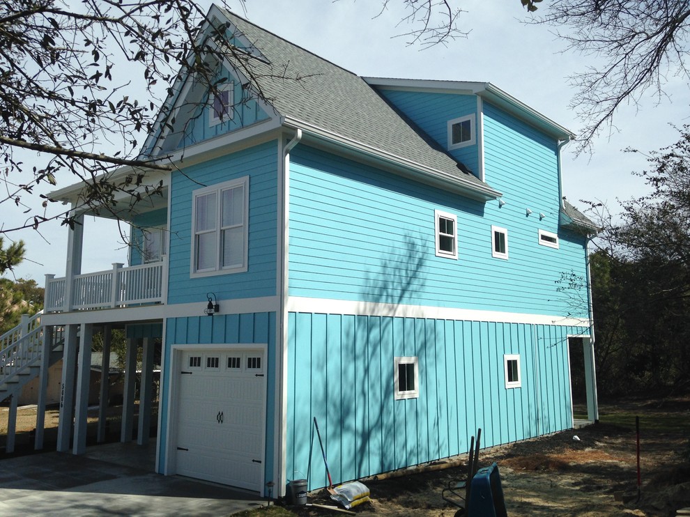 Photo of a large and blue beach style two floor house exterior in Other with wood cladding and a pitched roof.