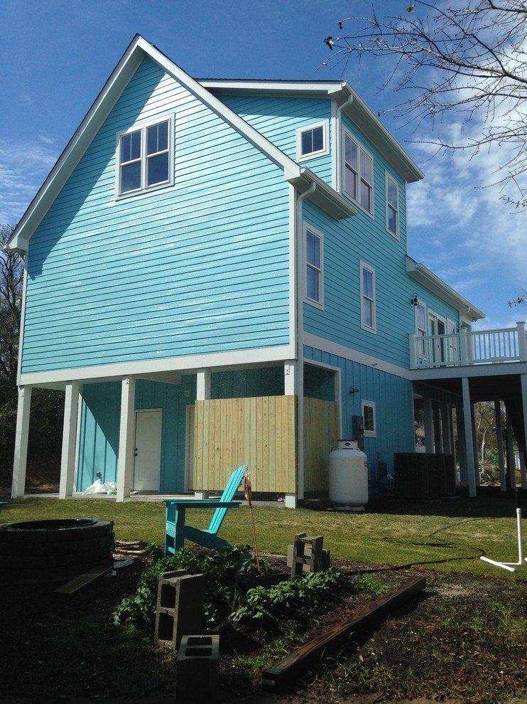 Foto de fachada azul marinera grande de dos plantas con revestimiento de madera y tejado a dos aguas