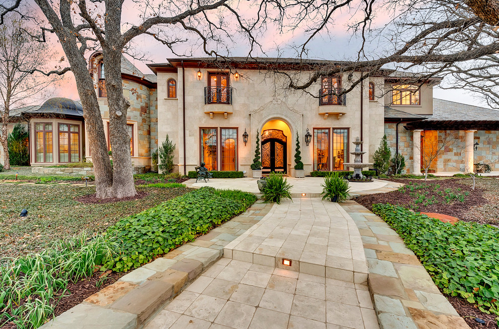 Design ideas for a beige mediterranean two floor house exterior in Dallas with a hip roof.