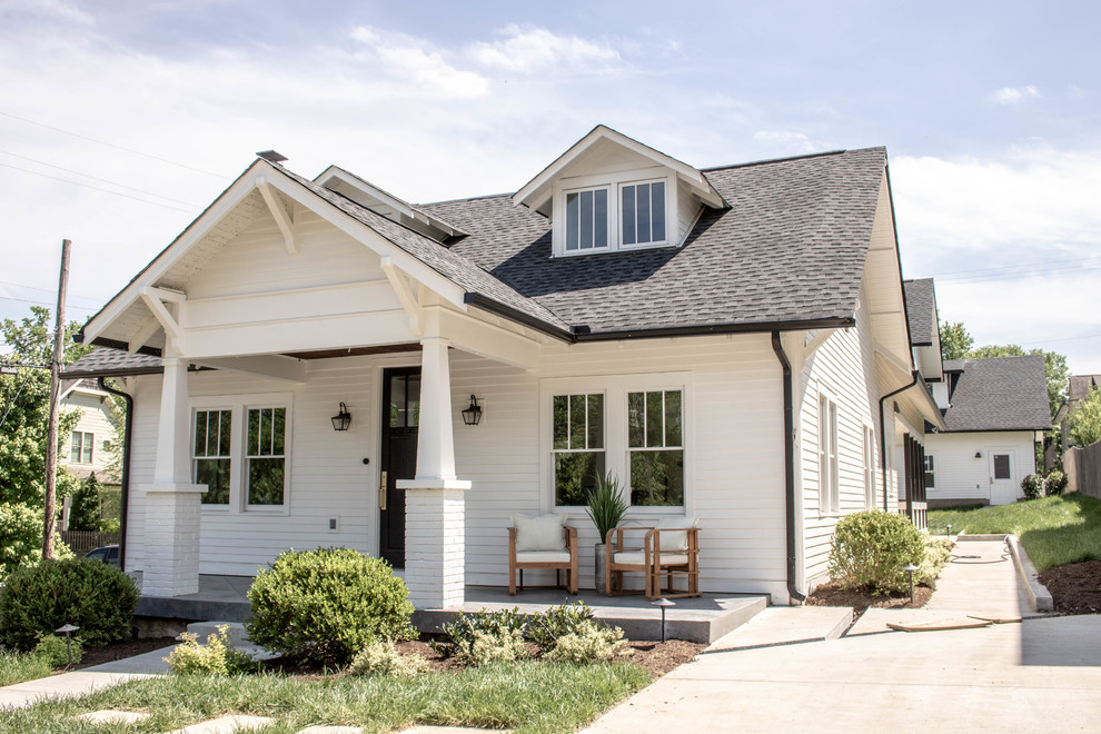 Imagen de fachada de casa blanca de estilo americano con tejado a dos aguas y tejado de teja de madera
