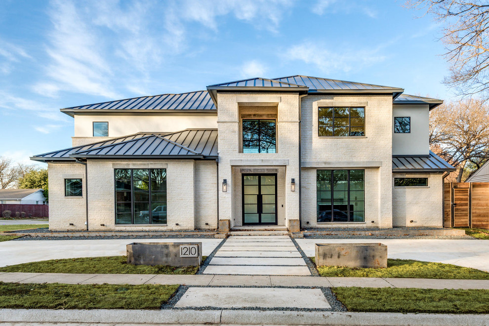 Imagen de fachada de casa blanca minimalista grande de dos plantas con revestimiento de piedra, tejado a dos aguas y tejado de metal