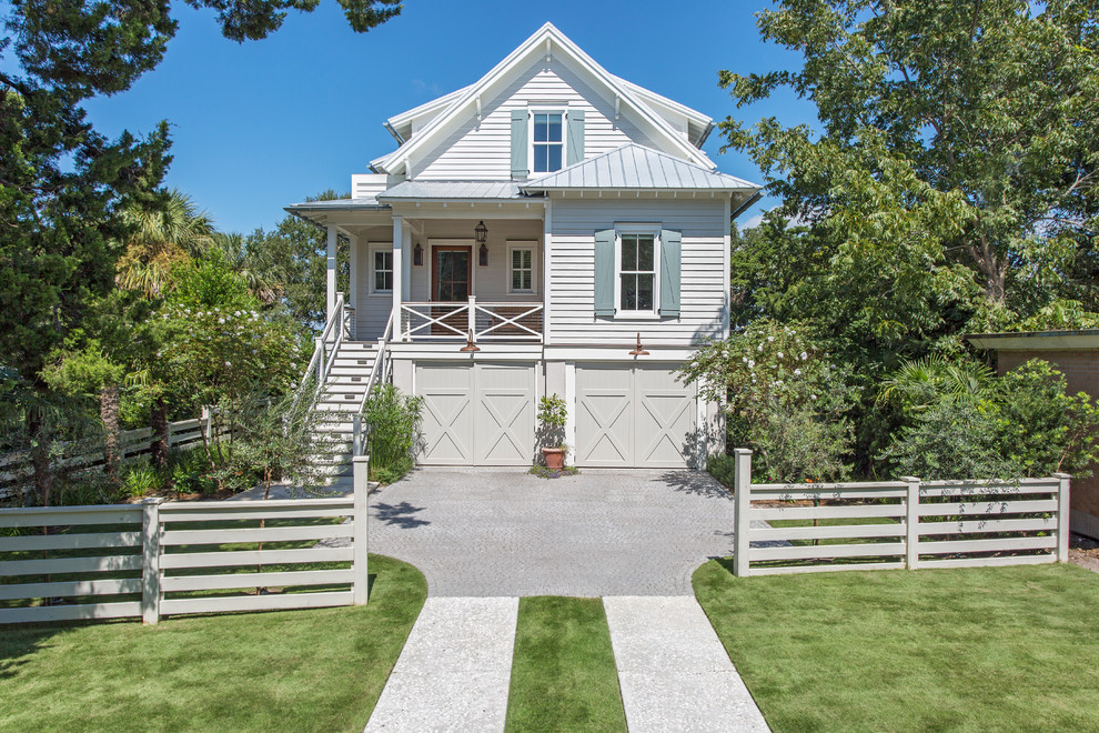 Diseño de fachada de casa blanca costera de tamaño medio con revestimiento de madera, tejado a dos aguas y tejado de metal