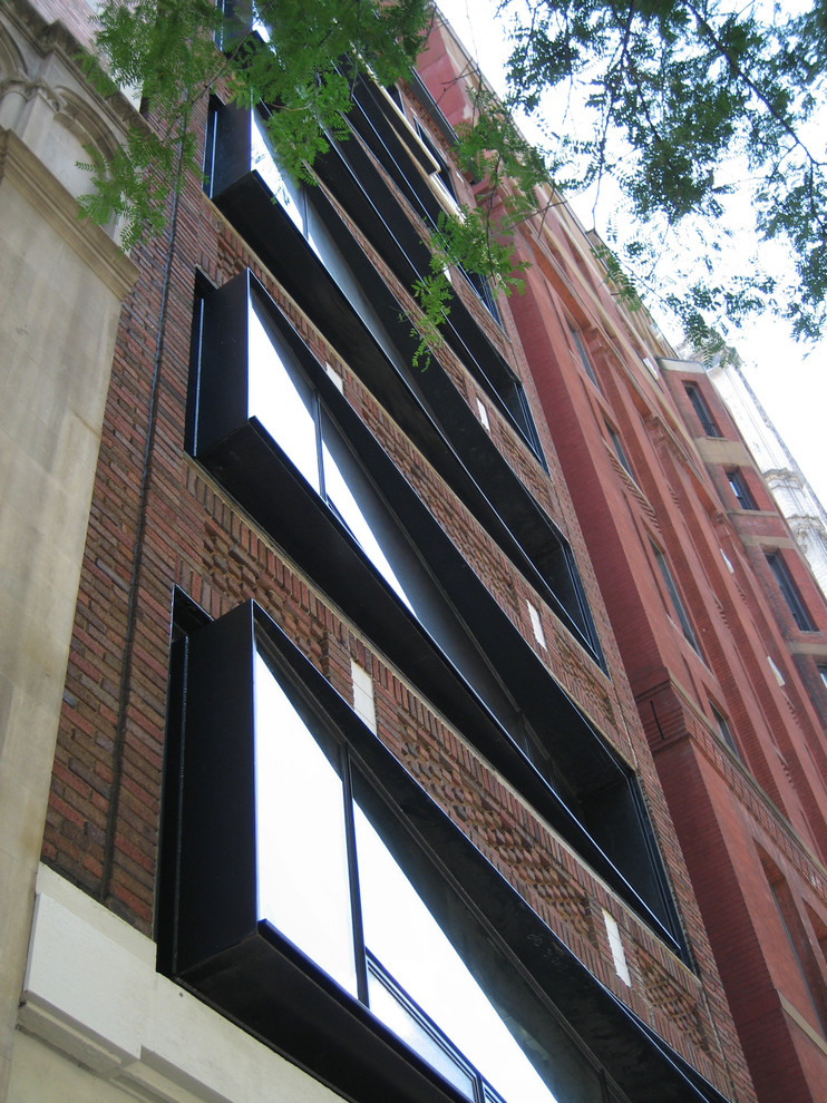 Cette image montre un façade d'immeuble minimaliste en brique de taille moyenne avec un toit plat et un toit en métal.
