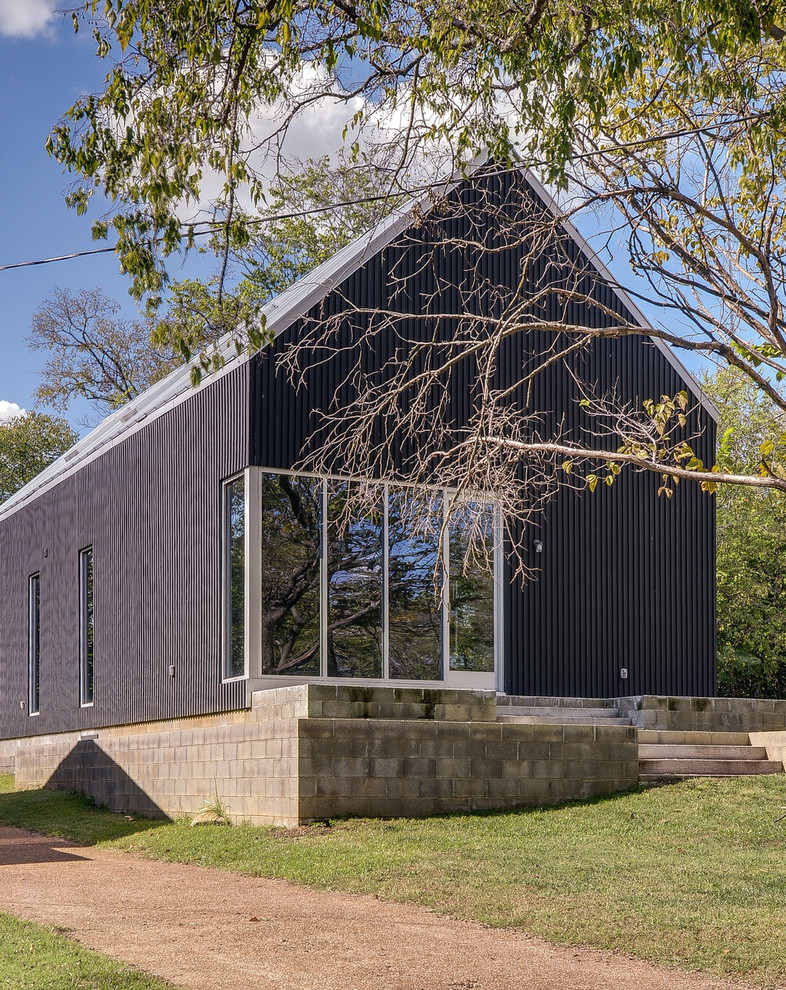 Foto della facciata di una casa nera contemporanea a due piani di medie dimensioni con rivestimento con lastre in cemento e tetto a capanna