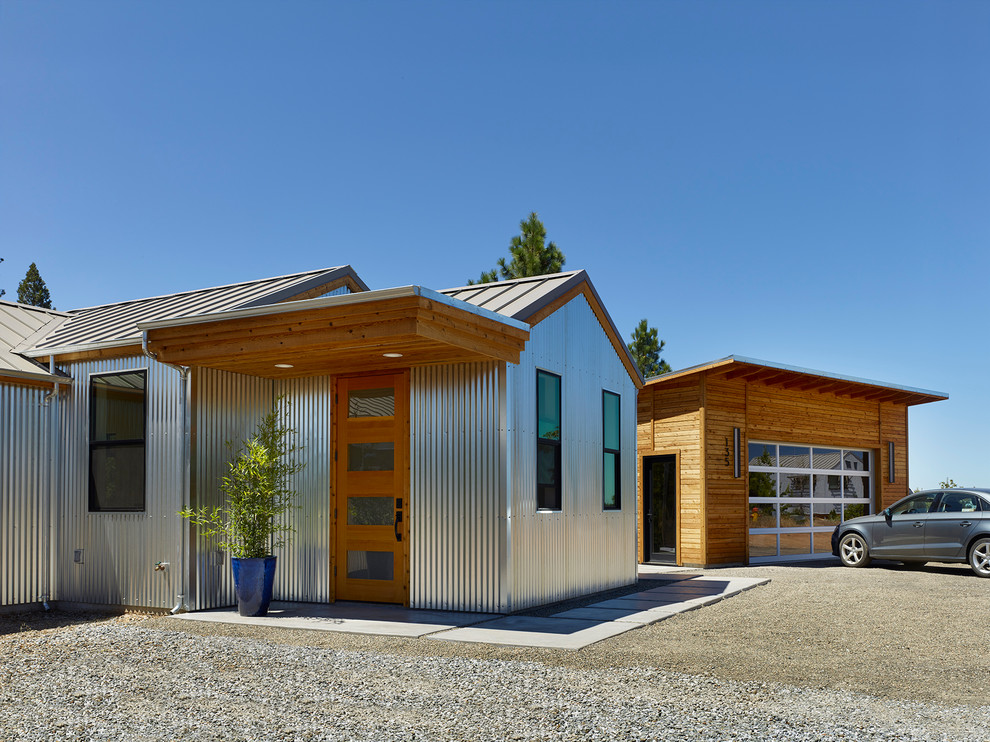 На фото: одноэтажный дом в стиле лофт с облицовкой из металла и двускатной крышей с