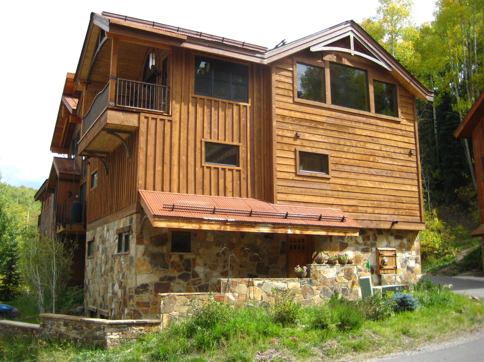 Пример оригинального дизайна: большой, двухэтажный, коричневый частный загородный дом в стиле рустика с комбинированной облицовкой, двускатной крышей и металлической крышей