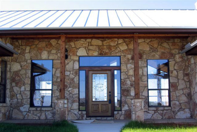 Réalisation d'une façade de maison beige champêtre en pierre de taille moyenne et de plain-pied.