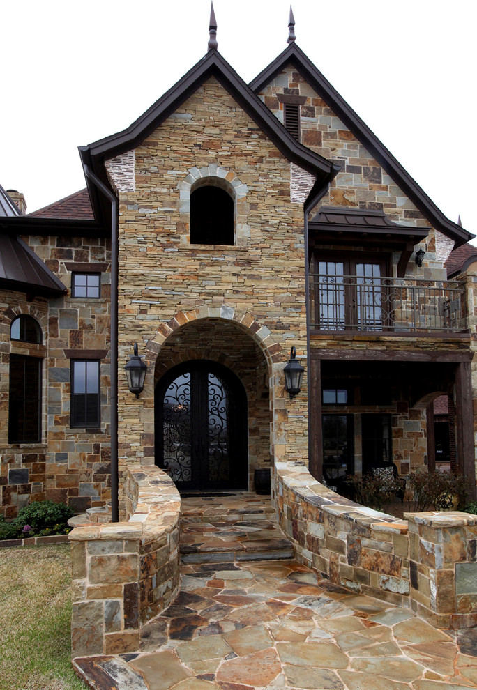 На фото: огромный, двухэтажный, коричневый дом в стиле фьюжн с облицовкой из камня