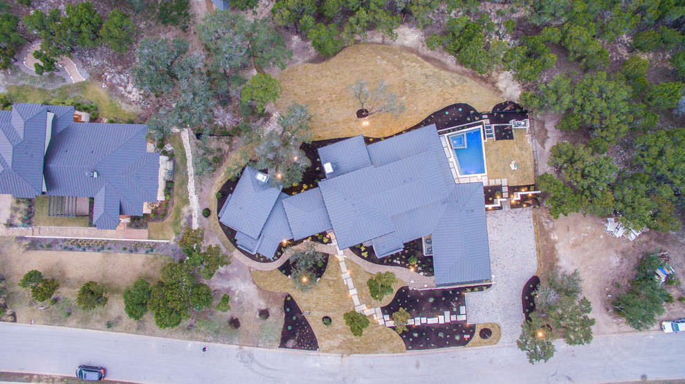 This is an example of a large contemporary two floor house exterior in Austin with stone cladding and a hip roof.