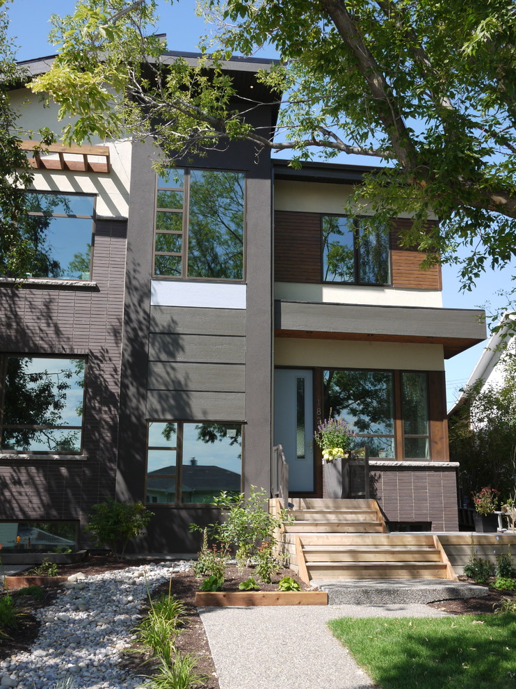 Réalisation d'une façade de maison multicolore design de taille moyenne et à un étage avec un revêtement mixte et un toit à quatre pans.