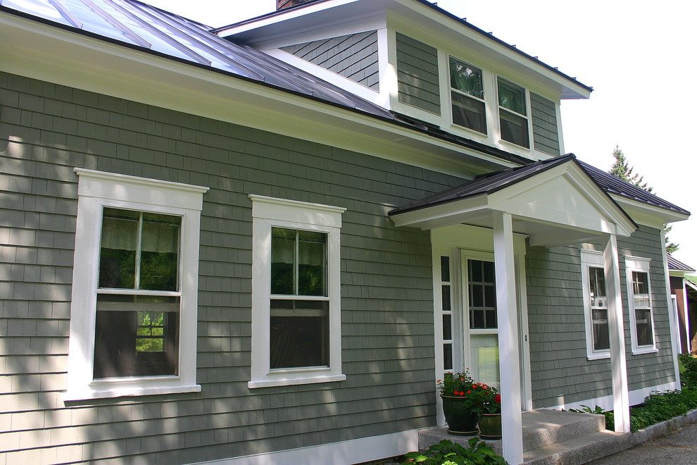 Exemple d'une façade de maison grise nature à un étage avec un toit en métal.