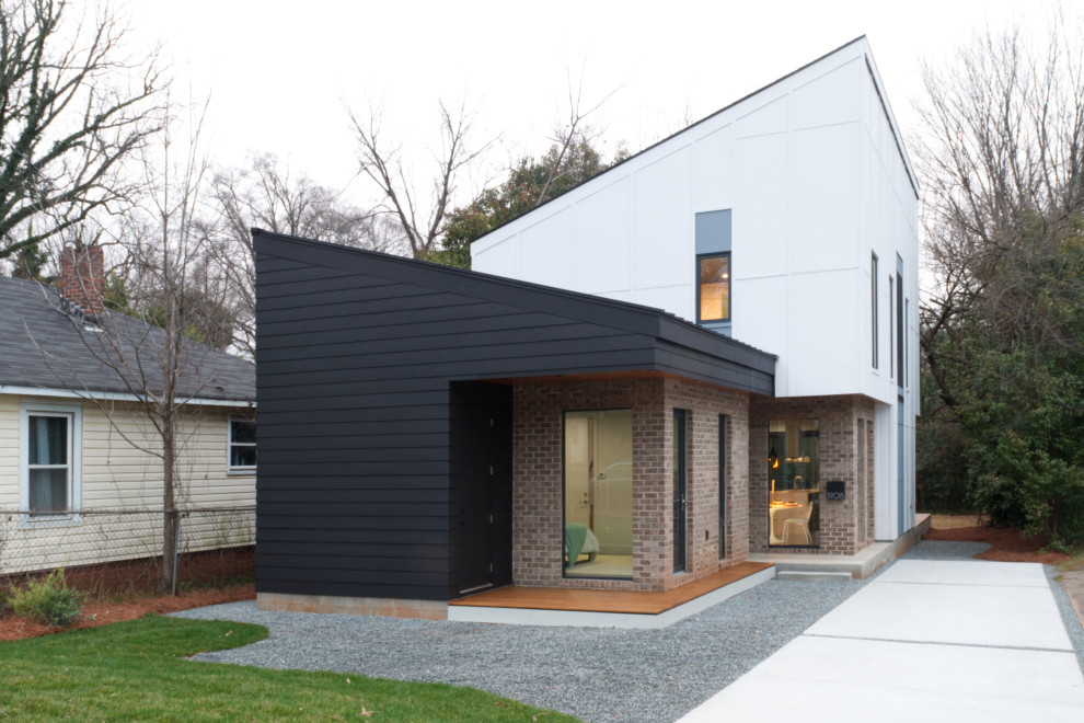 Idée de décoration pour une façade de maison multicolore minimaliste en brique de taille moyenne et à un étage avec un toit en appentis et un toit mixte.