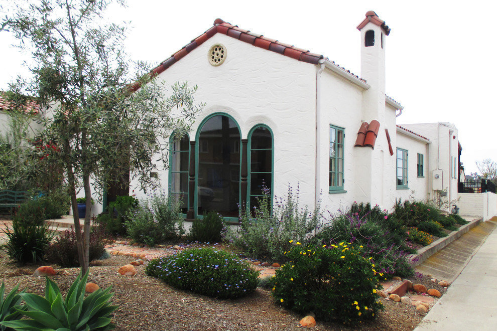 На фото: одноэтажный, белый дом в средиземноморском стиле с облицовкой из цементной штукатурки и двускатной крышей