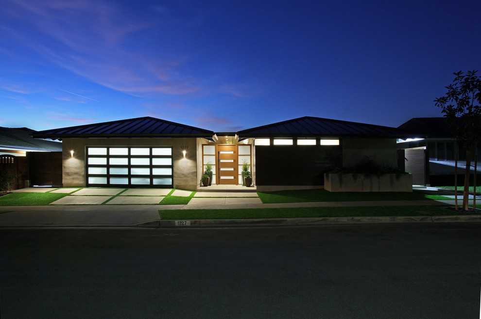 Ejemplo de fachada de casa gris moderna de tamaño medio de una planta con revestimiento de estuco, tejado a cuatro aguas y tejado de metal