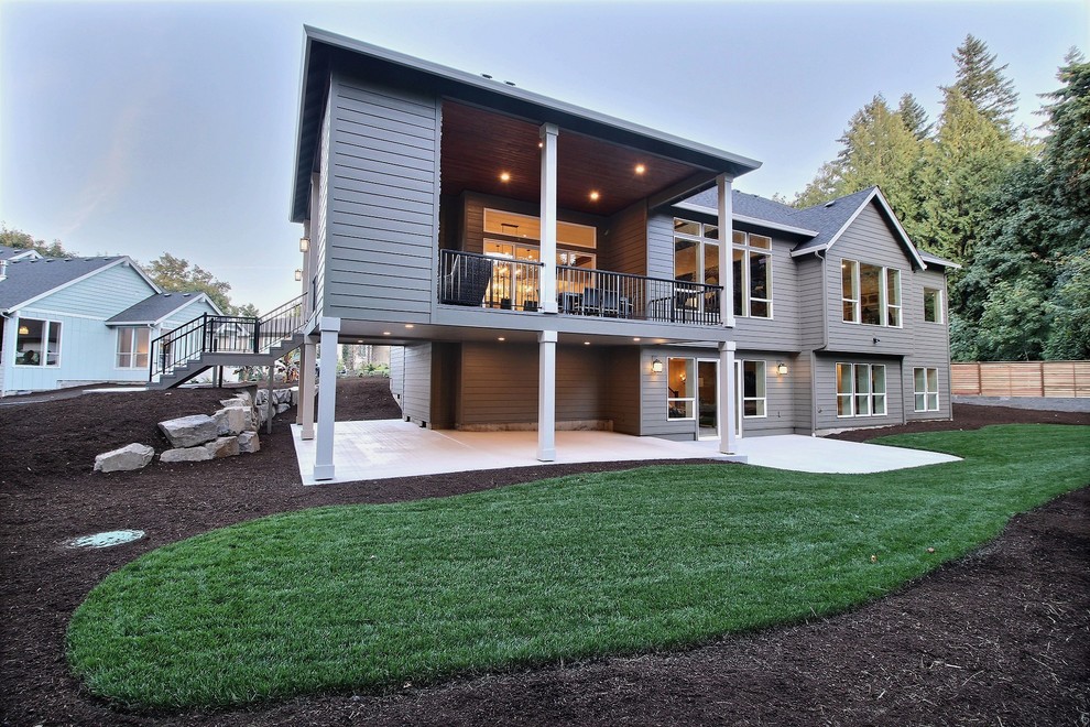 Modelo de fachada de casa gris tradicional extra grande a niveles con revestimientos combinados, tejado a dos aguas y tejado de teja de madera