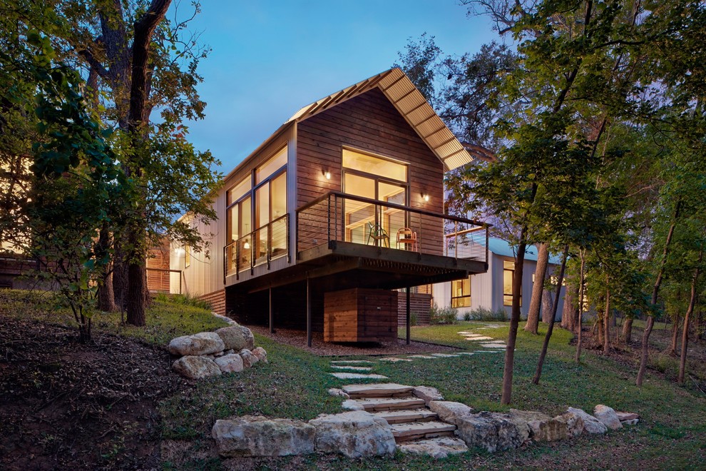 Photo of a contemporary house exterior in Austin with wood cladding and a pitched roof.