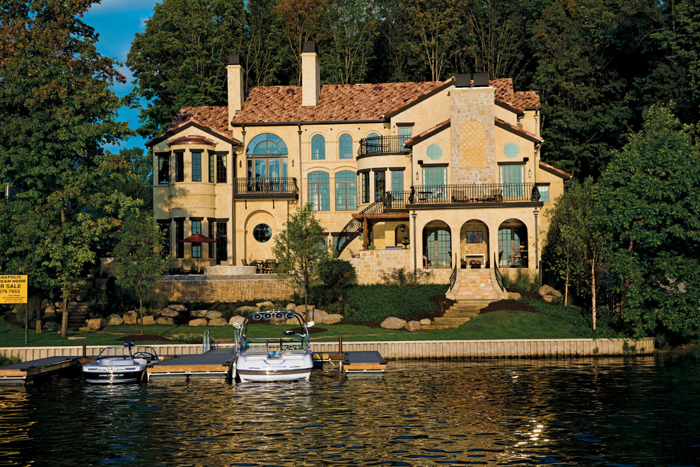 Imagen de fachada beige mediterránea de tamaño medio de dos plantas con revestimientos combinados y tejado a dos aguas